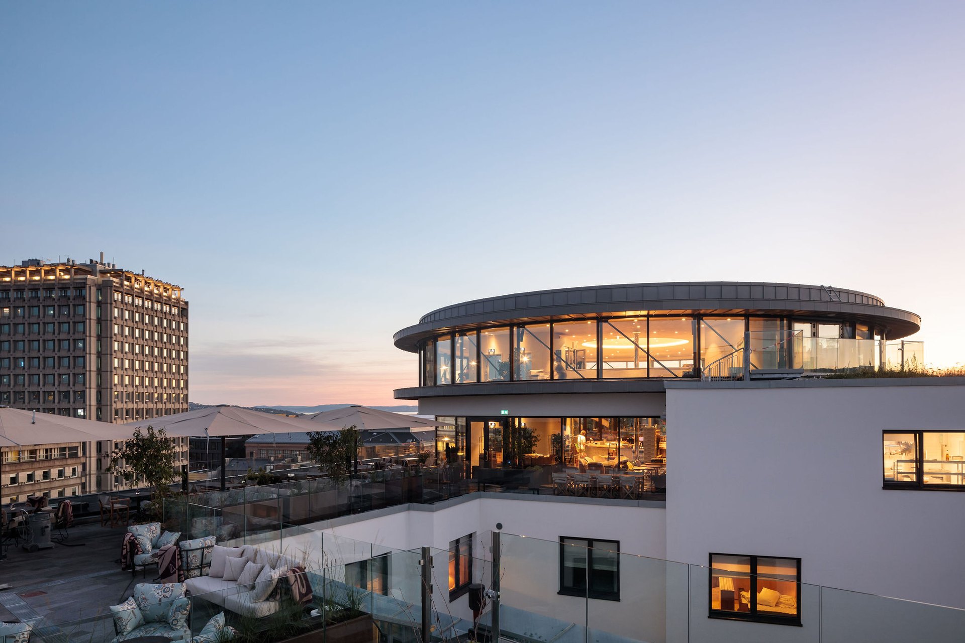 Sommerro’s rooftop terrace and round glass restaurant at dusk, with the fjord beyond